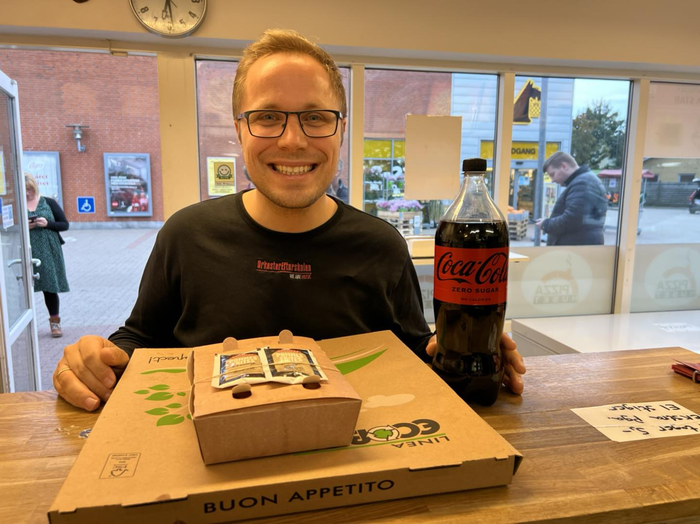 Ung mand med pizza og cola ved disken i Pizzahuset Holstebro